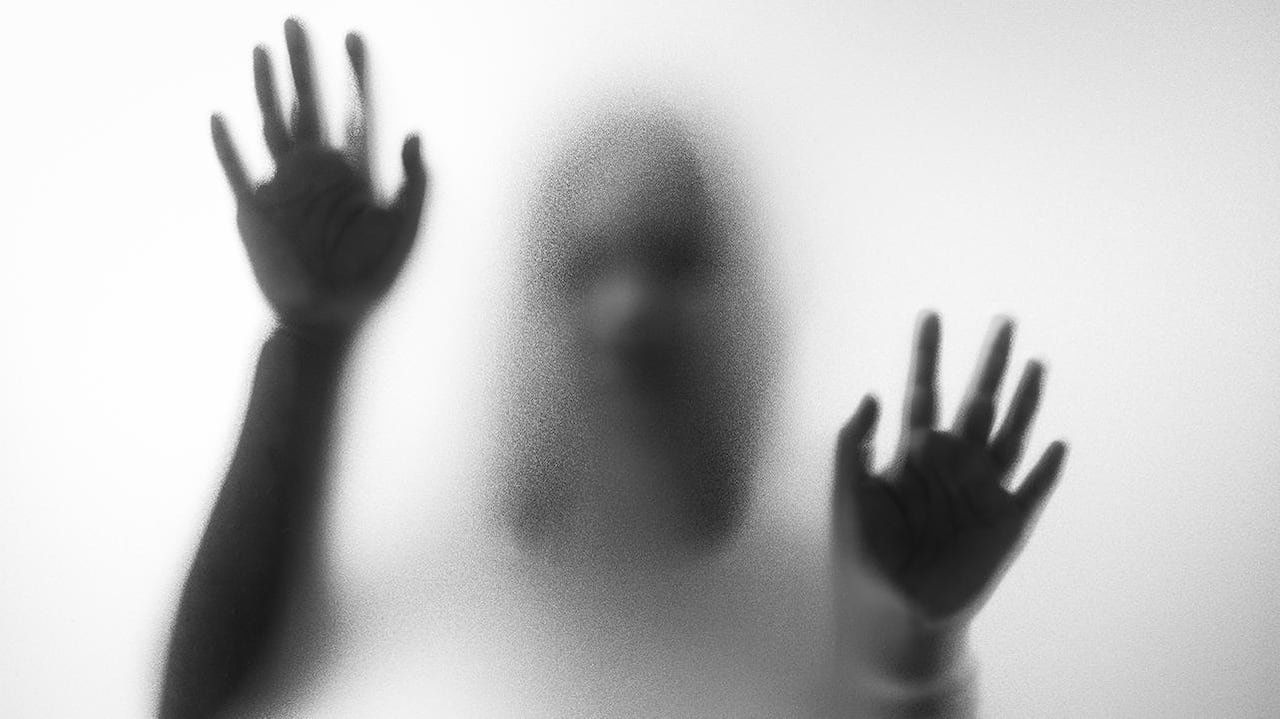 Blurry hands and body figure abstraction that looks like a ghost standing behind a glass pane with her hands on it